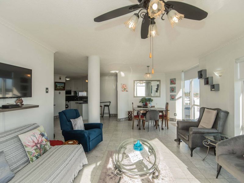Spacious open-plan living and dining area featuring tiled floors, a central structural column, and large sliding doors providing ample natural light.