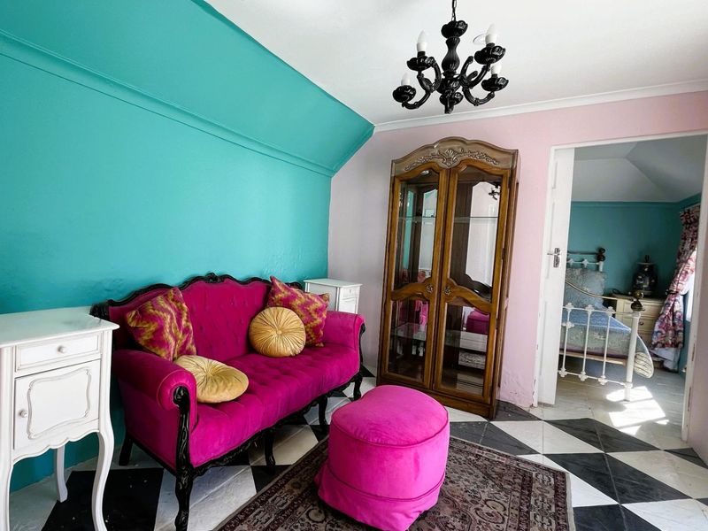 A bedroom featuring a sloped ceiling, checkerboard tile flooring, and a decorative chandelier, with an adjoining room visible through the doorway.