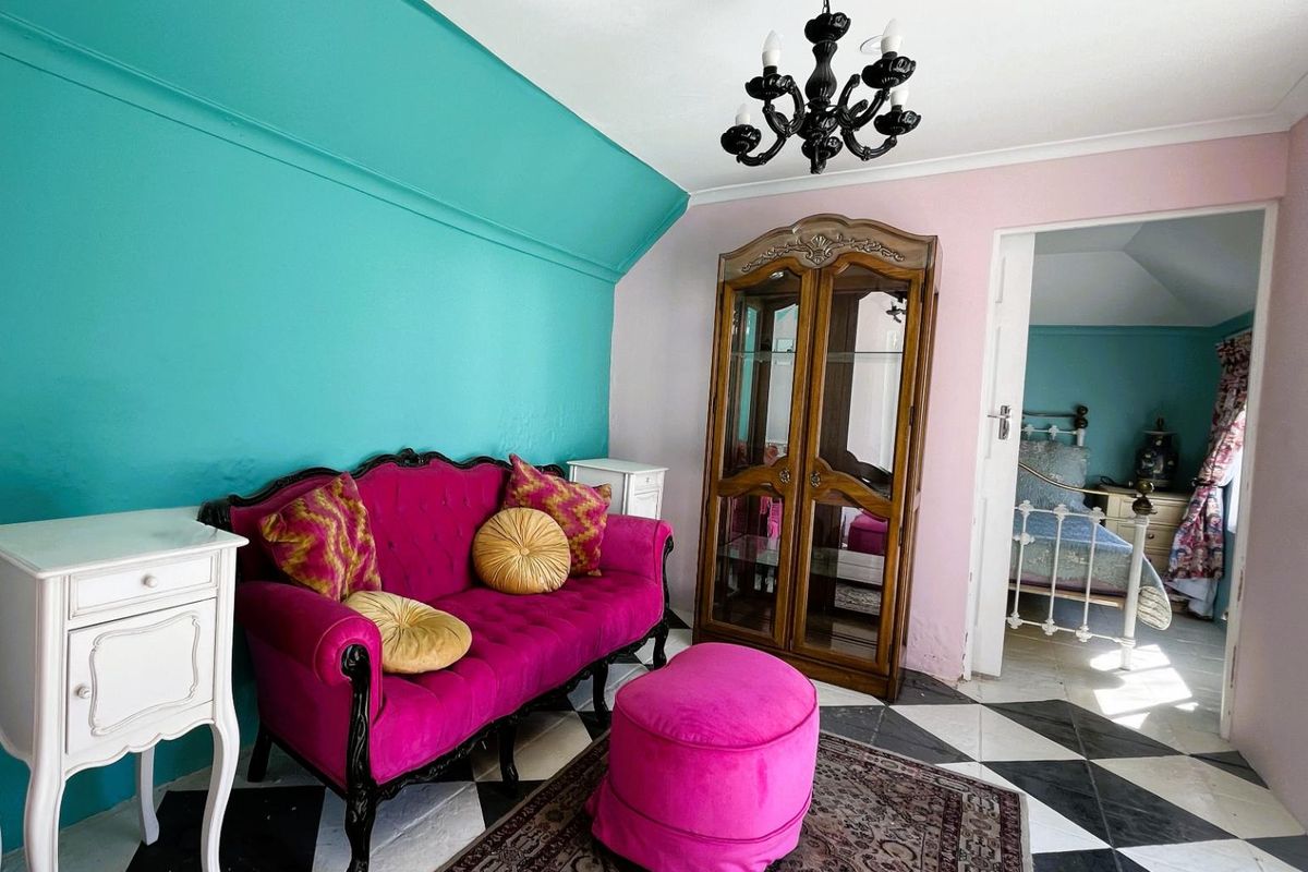 A bedroom featuring a sloped ceiling, checkerboard tile flooring, and a decorative chandelier, with an adjoining room visible through the doorway.