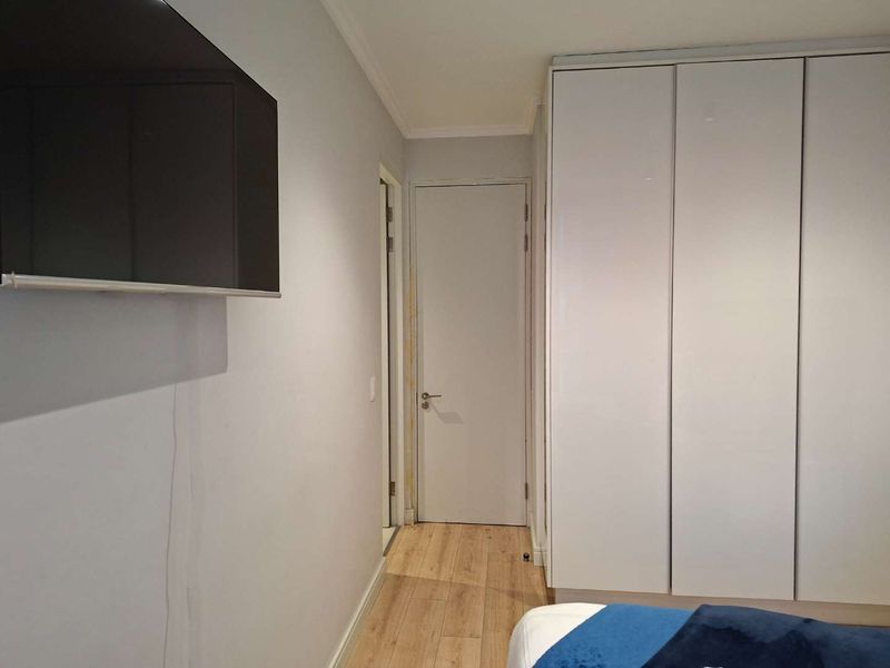 Bedroom featuring light laminate flooring and a large white built-in wardrobe with a clean, modern aesthetic.
