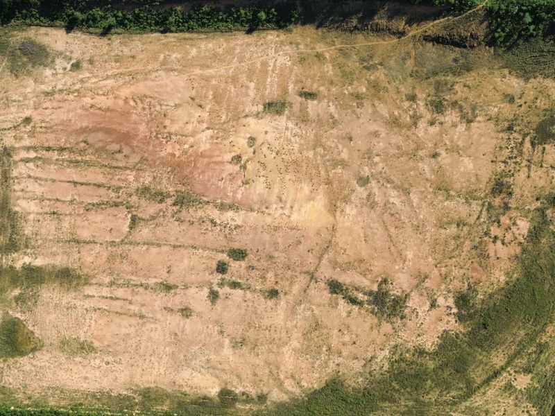 An aerial view of a large, cleared industrial plot of land with direct road access, suitable for future development.