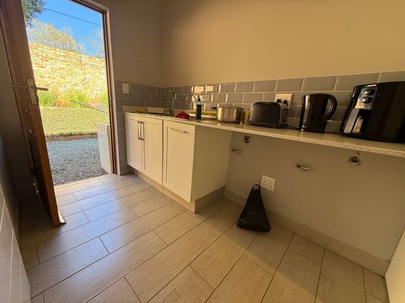 A functional scullery area featuring subway tile backsplash, stone countertops, and direct access to the rear garden.