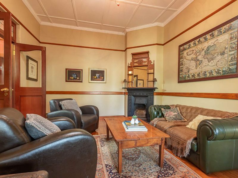 A classic living room featuring a traditional cast iron fireplace, timber dado rails, and elegant coffered ceilings, creating a warm and character-filled atmosphere.