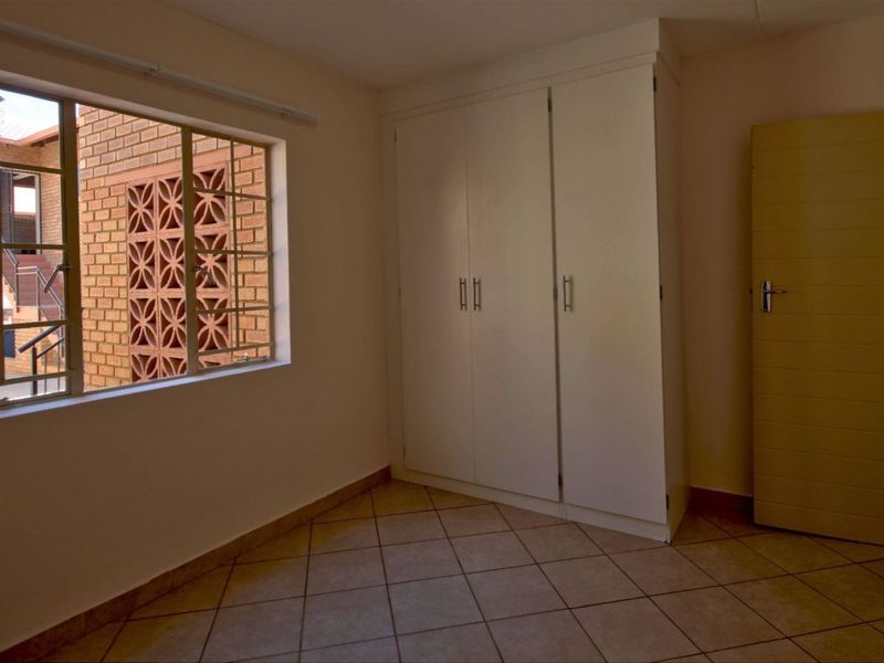 A bright, empty bedroom featuring tiled flooring and a built-in wardrobe, offering a clean canvas for personalization.