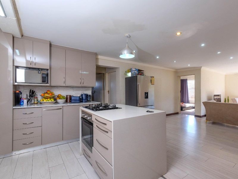 Open-plan kitchen featuring modern cabinetry, a central island with a gas hob and oven, and seamless flow into the adjacent living area.