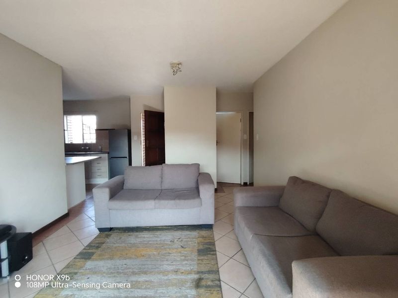 Open plan living area featuring tiled floors and a connected kitchen space with built-in cabinetry and countertops.