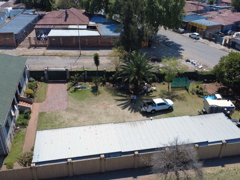 Aerial view of the property showing the main house, large garden area, paved driveway, and perimeter walling.