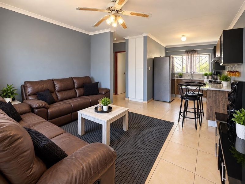 Open-plan living area featuring a modern kitchen with built-in cabinetry, tiled flooring, and a ceiling fan, creating a functional and cohesive living space.