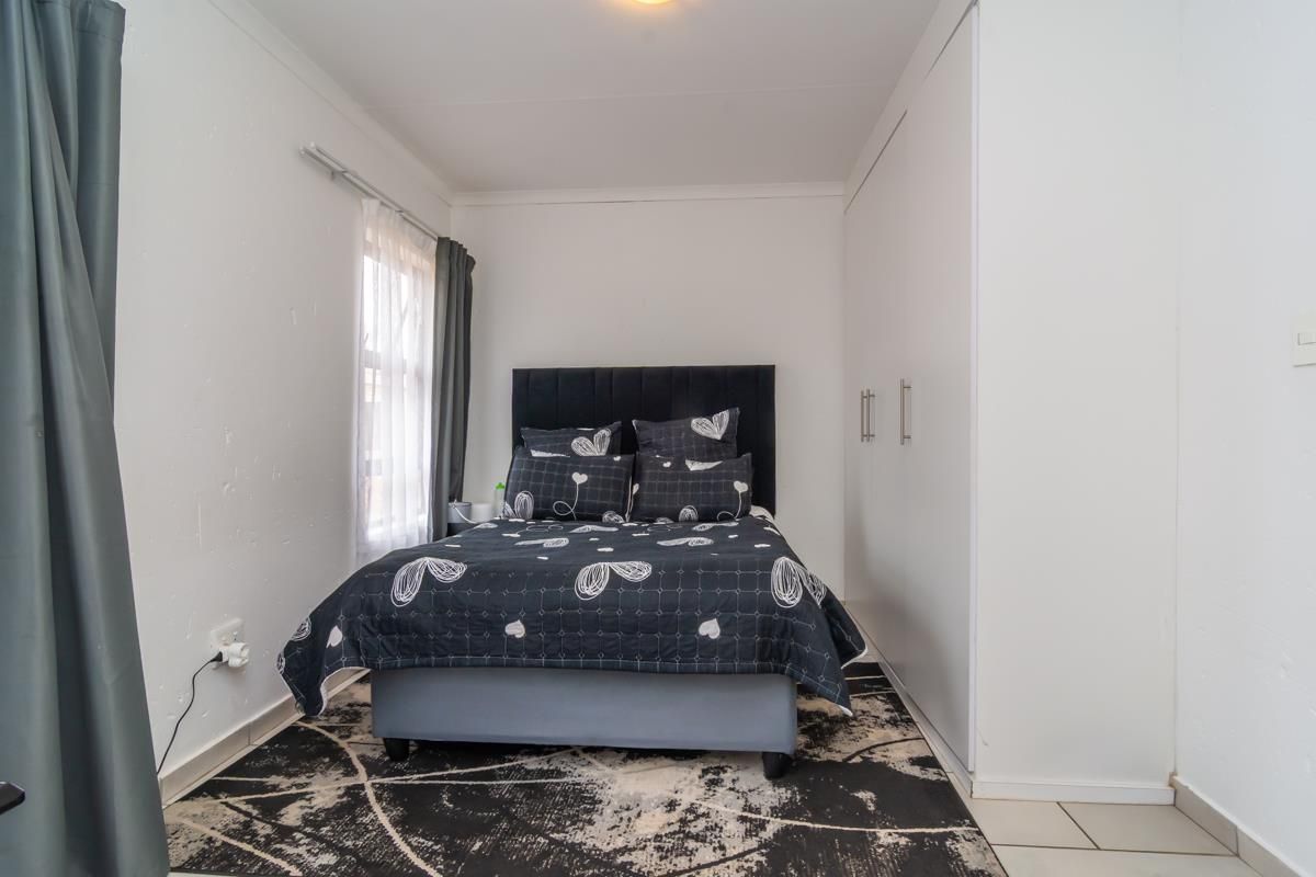 A compact bedroom featuring built-in floor-to-ceiling wardrobes and tiled flooring, offering a functional and clean living space.