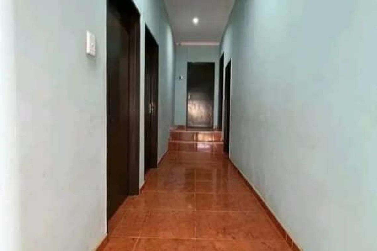 A long interior hallway featuring tiled flooring and multiple doorways leading to various rooms within the home.