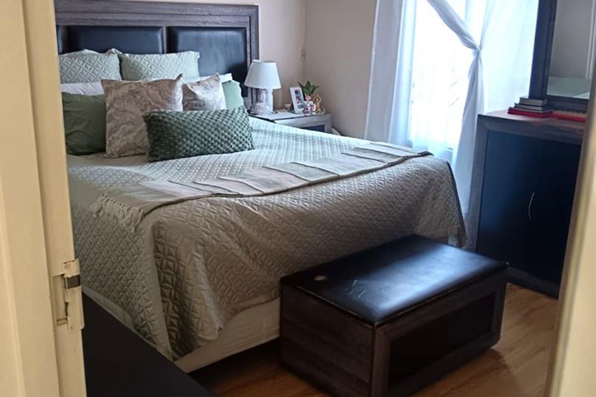 A well-maintained bedroom featuring laminate flooring, recessed ceiling lighting, and decorative coving, offering a comfortable and functional living space.