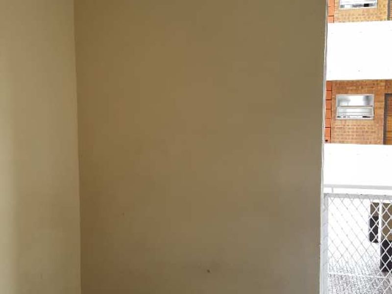 A compact, empty balcony area featuring tiled flooring and a metal security gate, providing access to the exterior.
