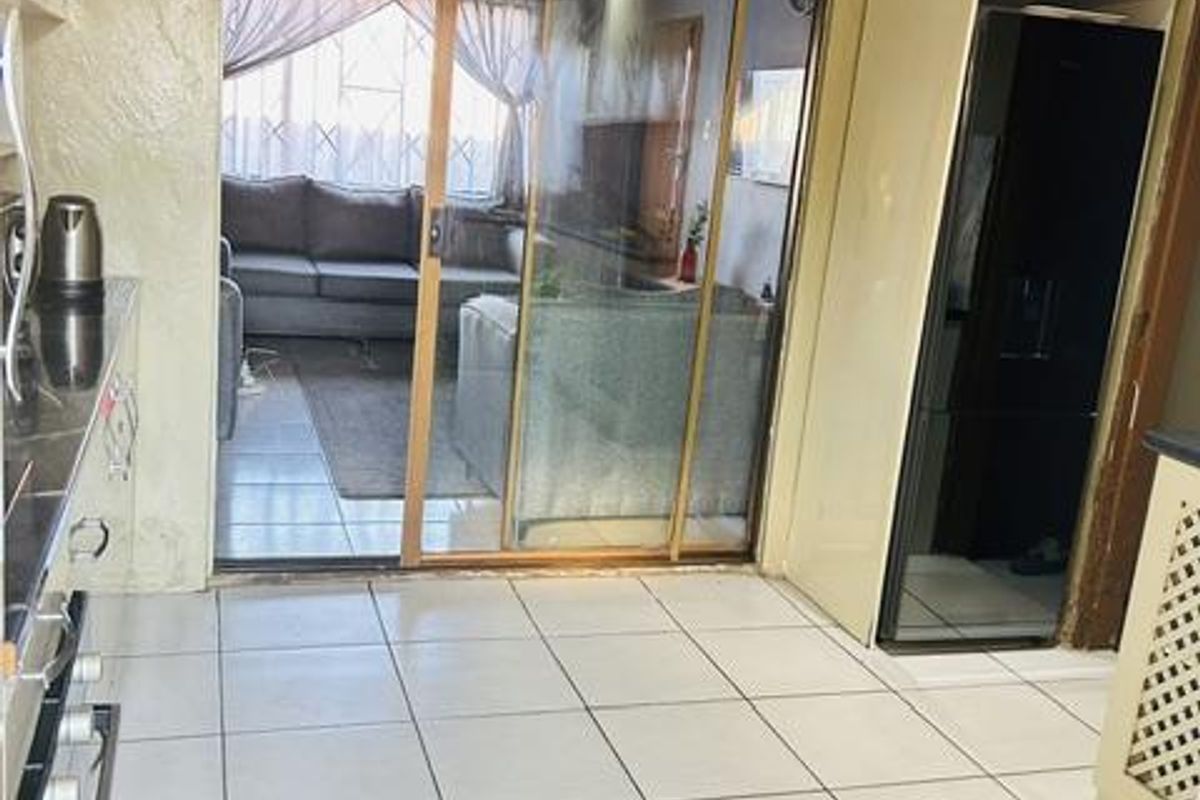 A kitchen area featuring tiled flooring, built-in cabinetry, and a sliding glass door providing access to the adjacent living space.