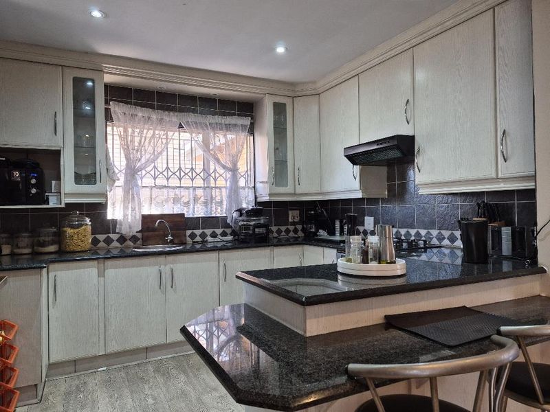 A functional kitchen featuring granite countertops, ample built-in cabinetry, a tiled backsplash, and an integrated extractor fan.
