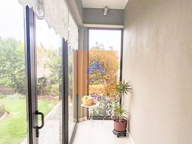 A bright, covered patio area featuring tiled flooring and large sliding glass doors that provide direct access to the garden.