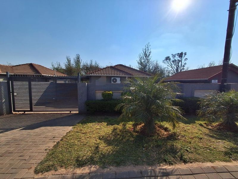 Front view of the property featuring a paved driveway, secure sliding gate, boundary wall, and tiled roof structure.