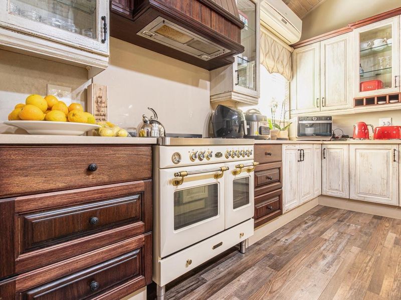 A well-appointed kitchen featuring a vintage-style gas range, custom cabinetry with a mix of wood and distressed finishes, and durable laminate flooring.