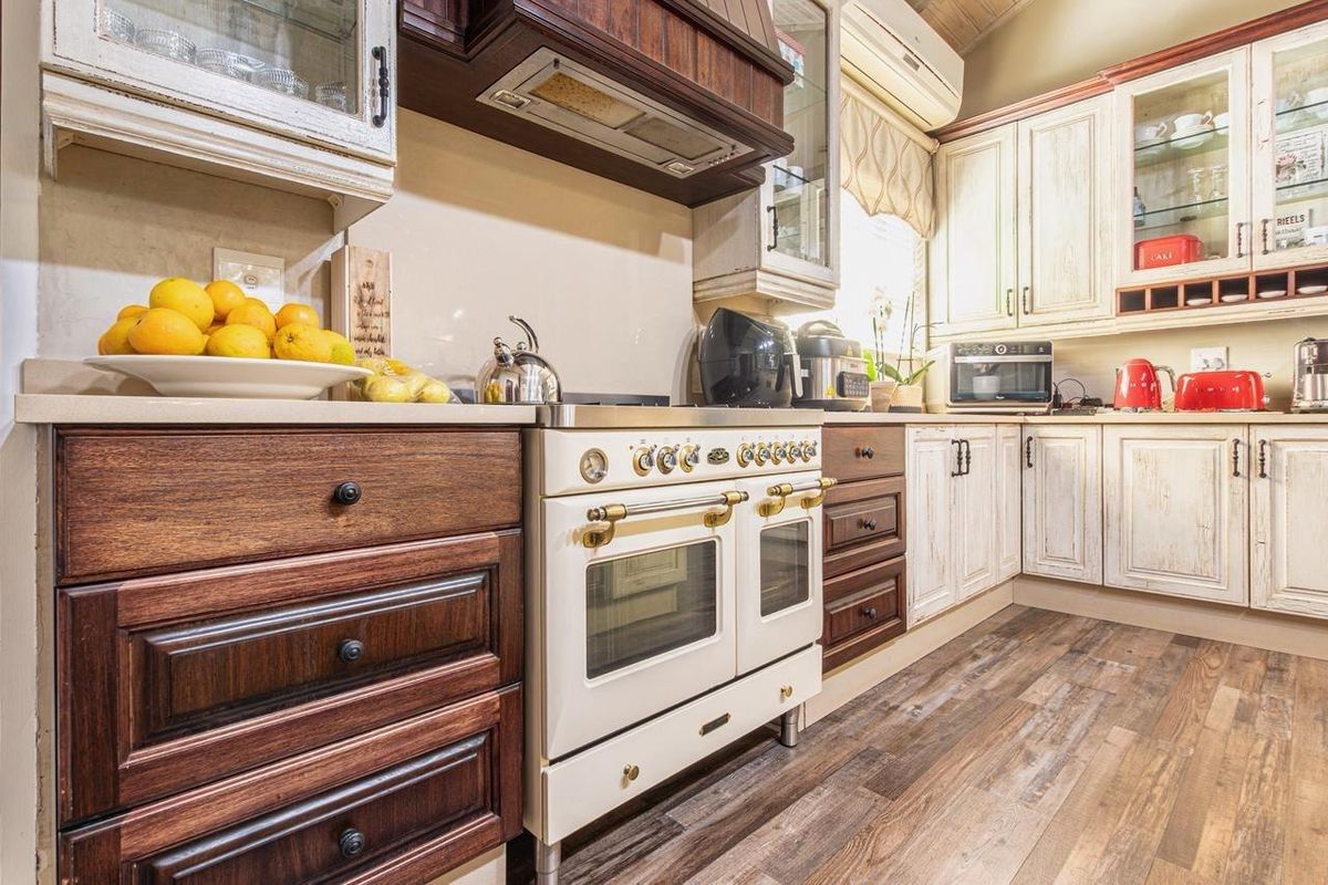 A well-appointed kitchen featuring a vintage-style gas range, custom cabinetry with a mix of wood and distressed finishes, and durable laminate flooring.