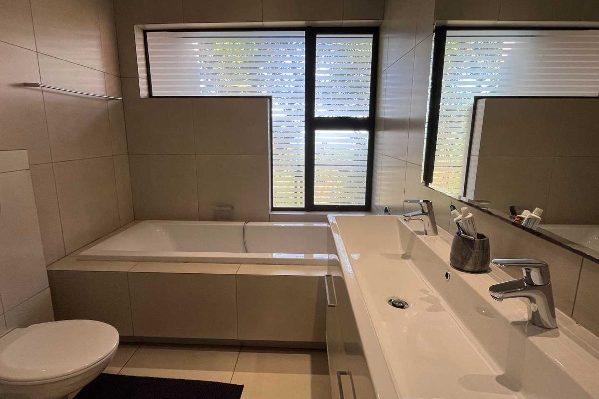 Modern bathroom featuring a built-in bathtub, a sleek vanity with a double basin, and large format wall tiles.