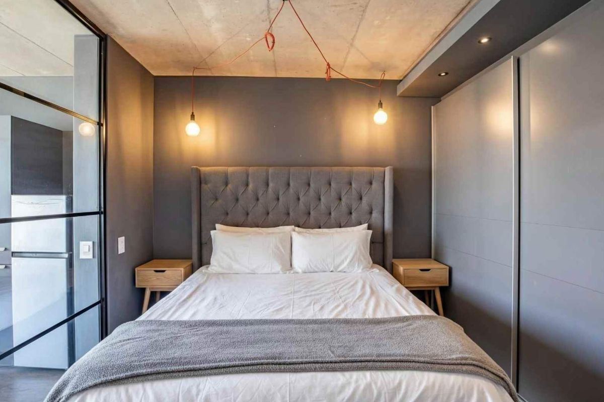 Modern bedroom featuring an exposed concrete ceiling, built-in sliding wardrobe, and a sleek glass partition wall, creating a contemporary and stylish living space.