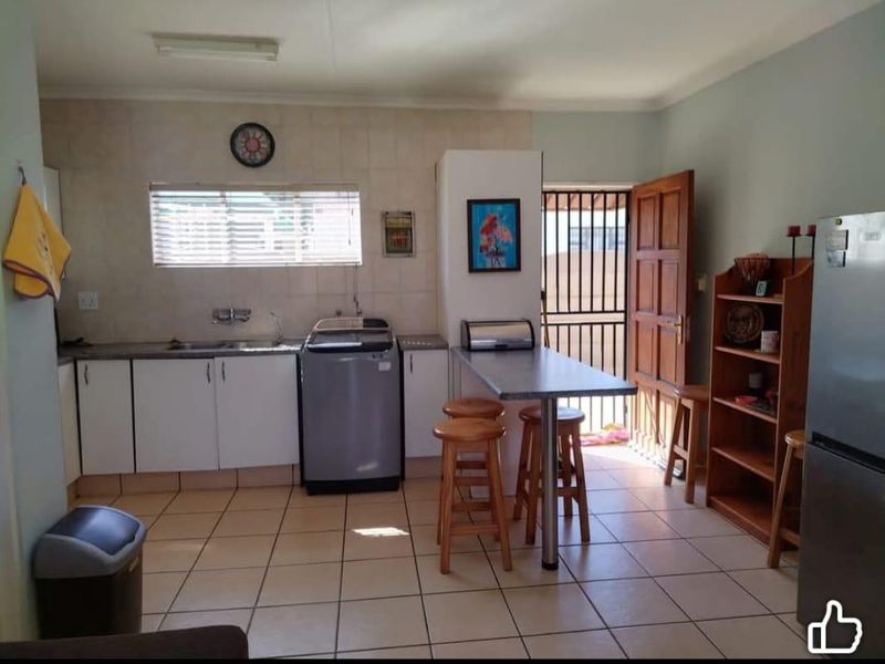 Functional kitchen featuring tiled flooring, built-in cabinetry, a stainless steel sink, and direct access to the exterior via a security gate.