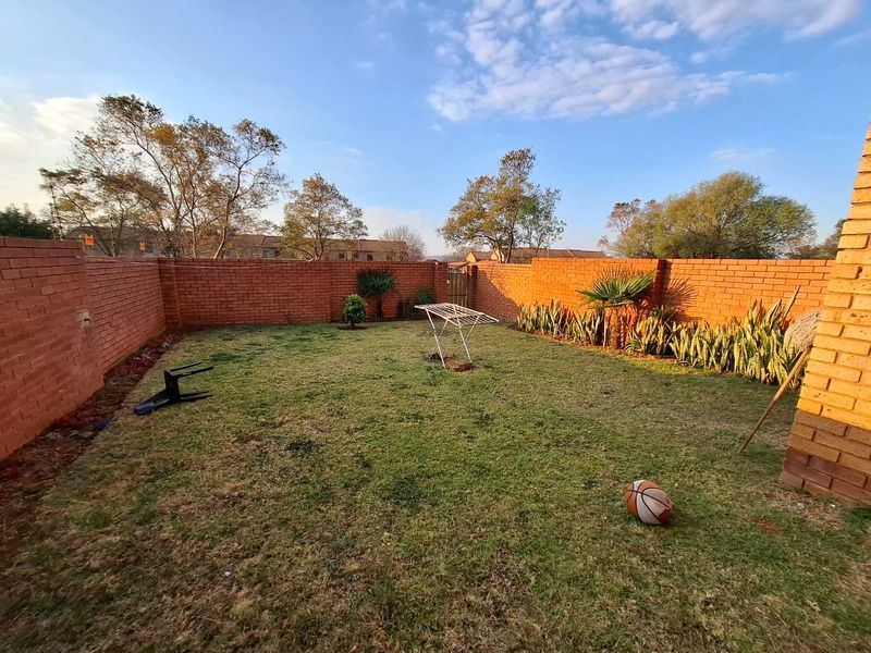 A private rear garden featuring a lawn area enclosed by high brick boundary walls.