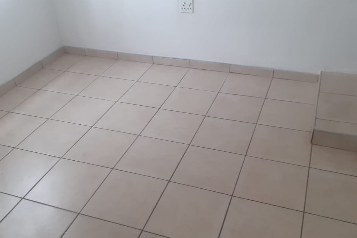 An empty room featuring neutral ceramic floor tiles, matching tiled skirting, and a clean white wall finish.