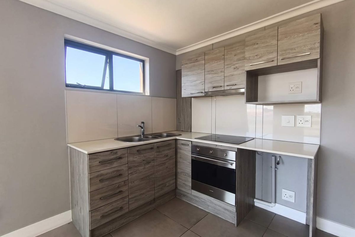 Modern kitchen featuring wood-look cabinetry, stone-effect countertops, integrated electric oven and hob, and tiled flooring in a clean, contemporary layout.