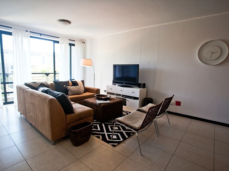 A bright living room featuring tiled flooring and a large sliding glass door that provides access to an outdoor area.