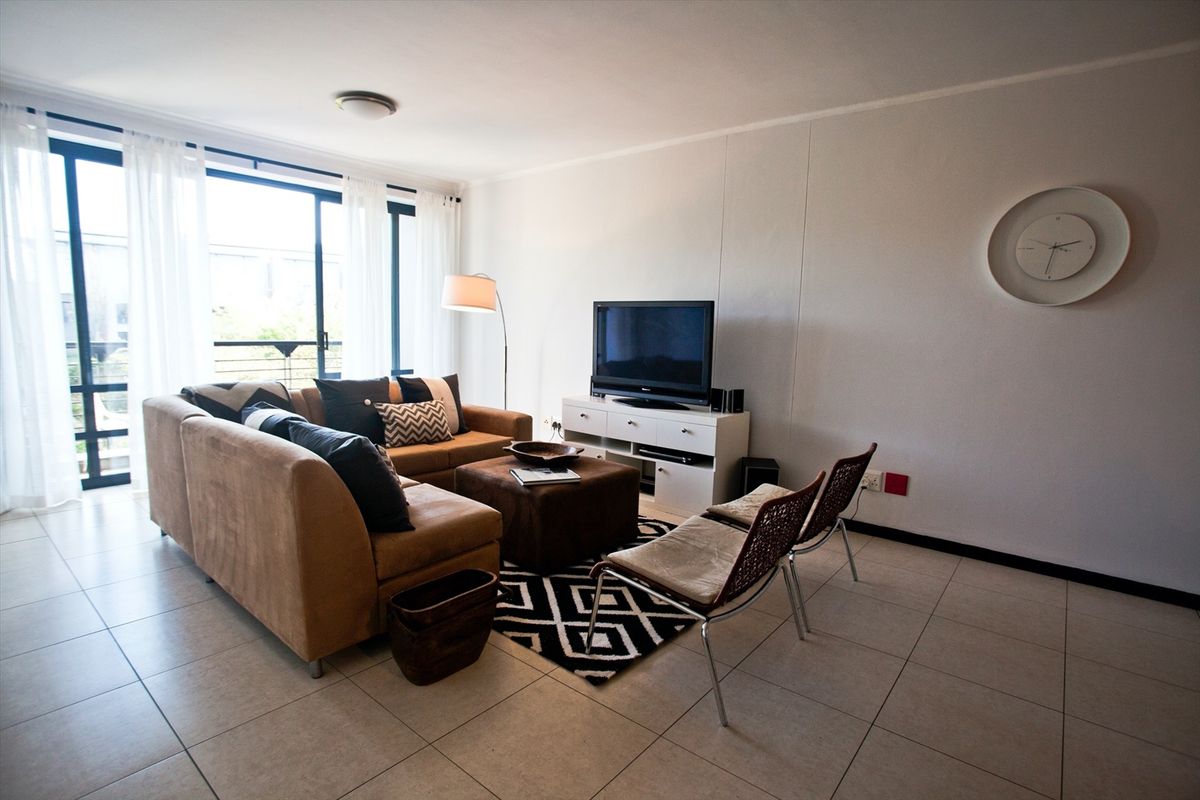 A bright living room featuring tiled flooring and a large sliding glass door that provides access to an outdoor area.