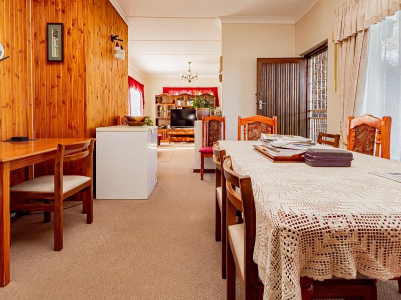 Open plan living and dining area featuring timber wall paneling, carpeted flooring, and coved cornicing, providing a functional and connected living space.