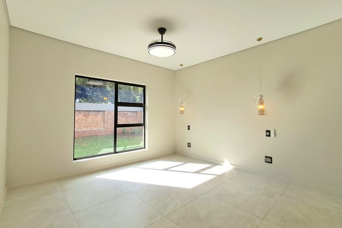 A bright, modern bedroom featuring large windows, neutral tiled flooring, and contemporary ceiling and pendant lighting fixtures.