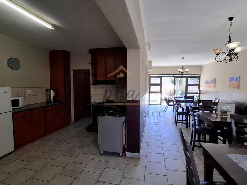 Open-plan kitchen and dining area featuring tiled flooring, built-in cabinetry, and direct access to the outdoor patio through sliding glass doors.
