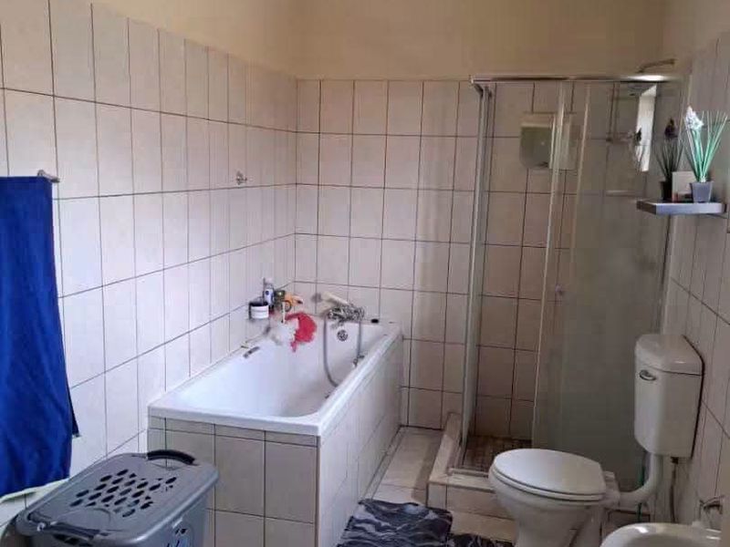 A functional bathroom featuring a built-in bathtub, separate shower enclosure, toilet, and pedestal basin with tiled walls and flooring.