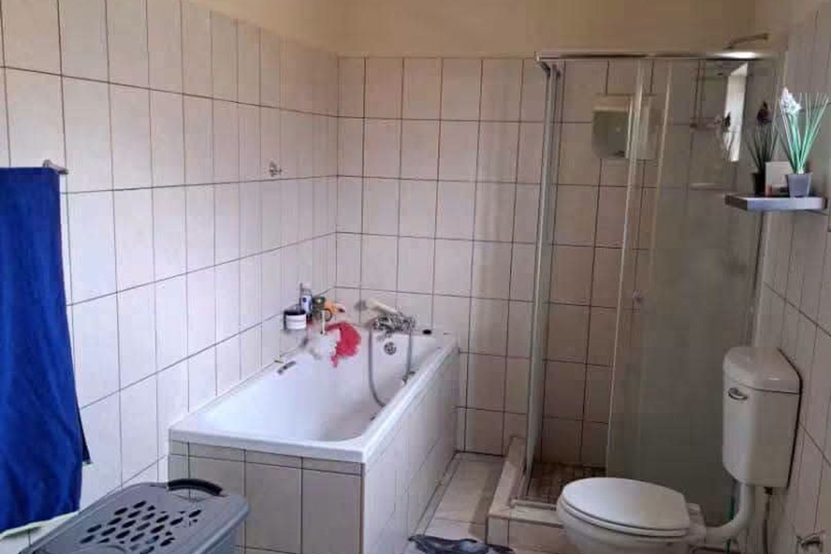 A functional bathroom featuring a built-in bathtub, separate shower enclosure, toilet, and pedestal basin with tiled walls and flooring.