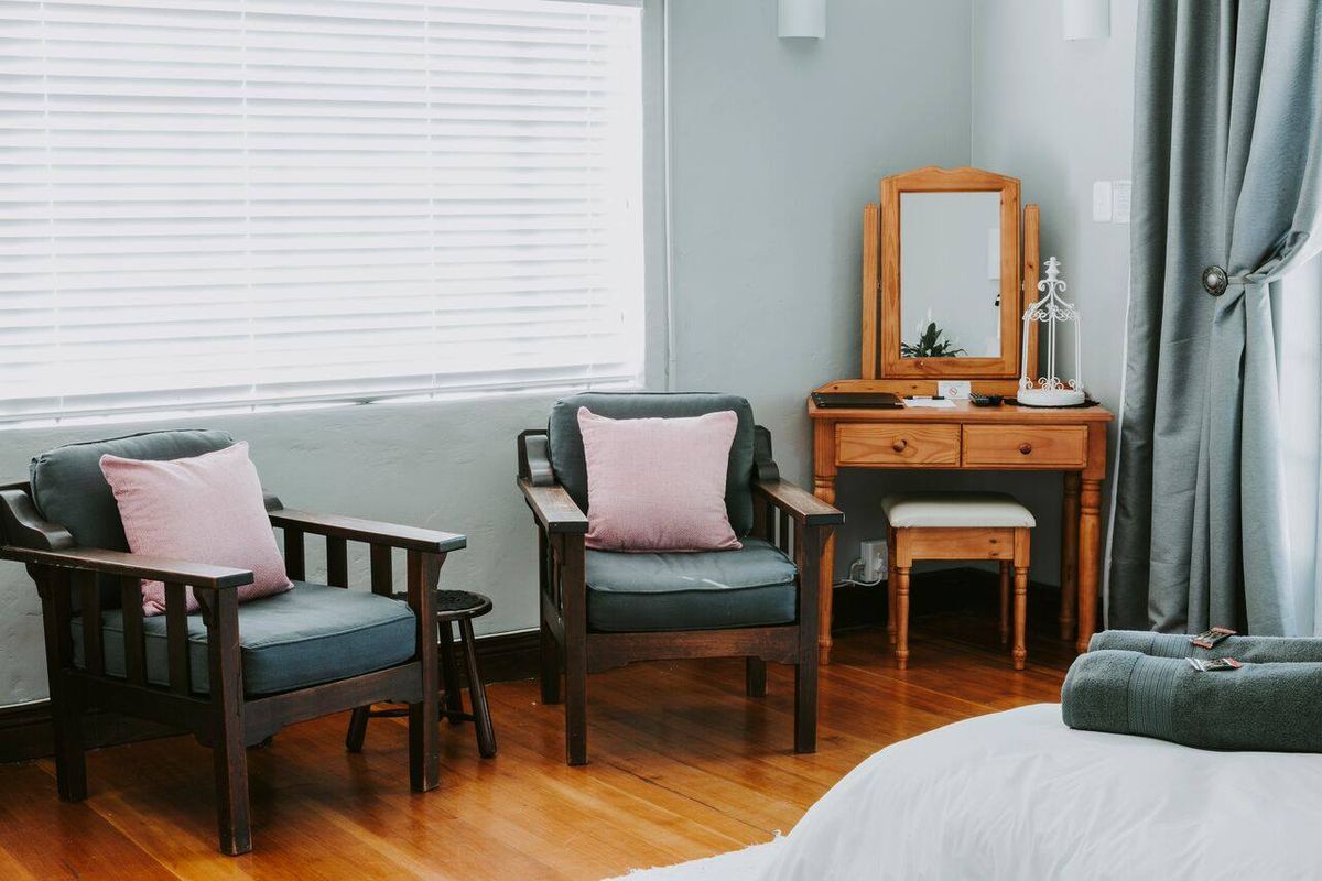 A well-maintained bedroom featuring warm hardwood flooring, neutral wall tones, and venetian blinds, creating a comfortable and inviting living space.