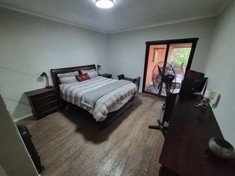 A bedroom featuring laminate flooring and a sliding door providing access to an outdoor area.