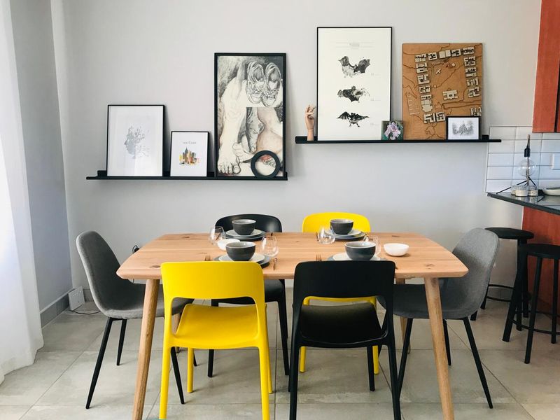 A bright and modern dining area featuring neutral tiled flooring, minimalist floating wall shelves, and a clean subway tile backsplash.
