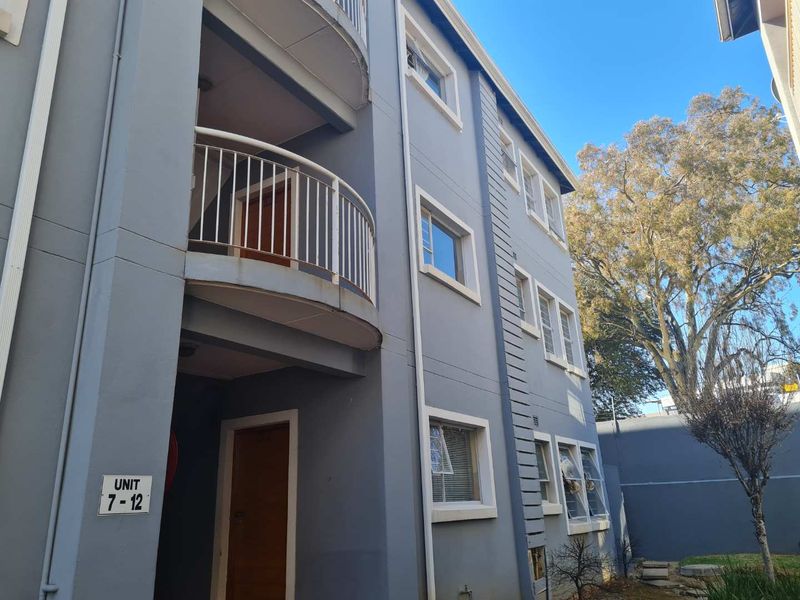 Exterior view of a multi-story apartment building featuring a balcony with metal railings and standard casement windows.