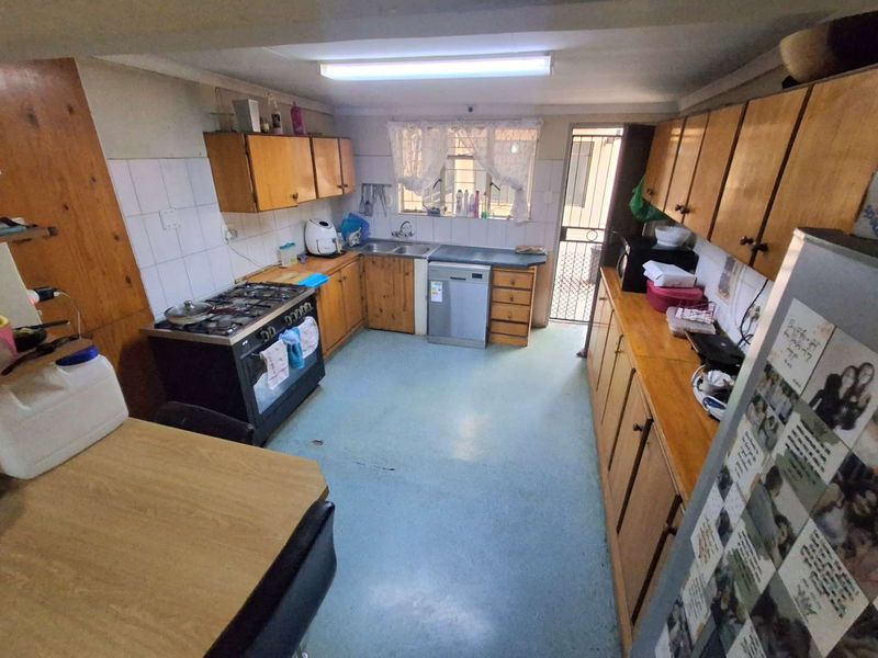 A functional kitchen featuring wooden cabinetry, a gas stove, and direct access to an exterior security gate.