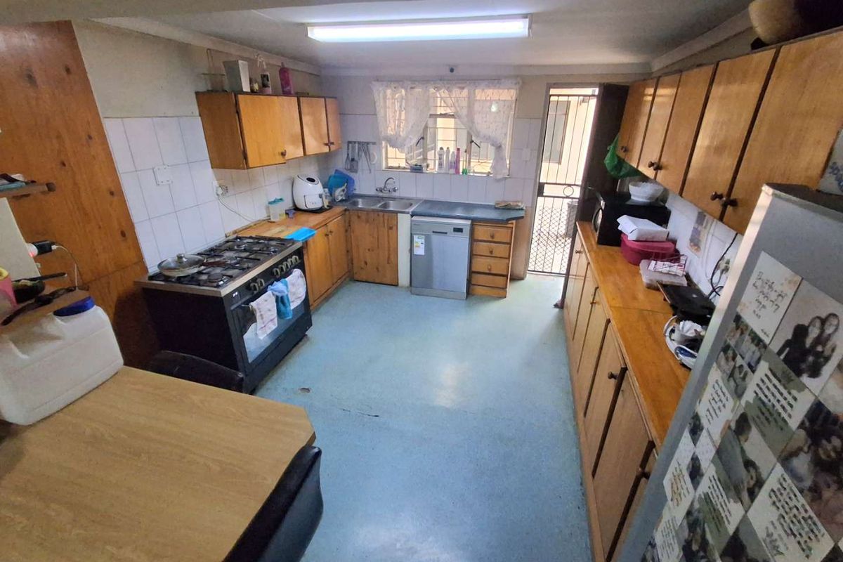 A functional kitchen featuring wooden cabinetry, a gas stove, and direct access to an exterior security gate.