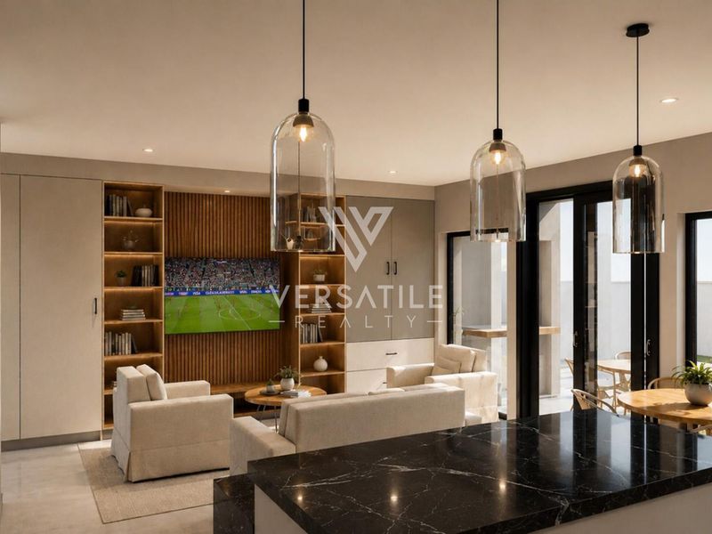 Modern open-plan living area featuring a sleek black marble kitchen island, custom built-in cabinetry, and seamless access to the outdoor patio through sliding glass doors.