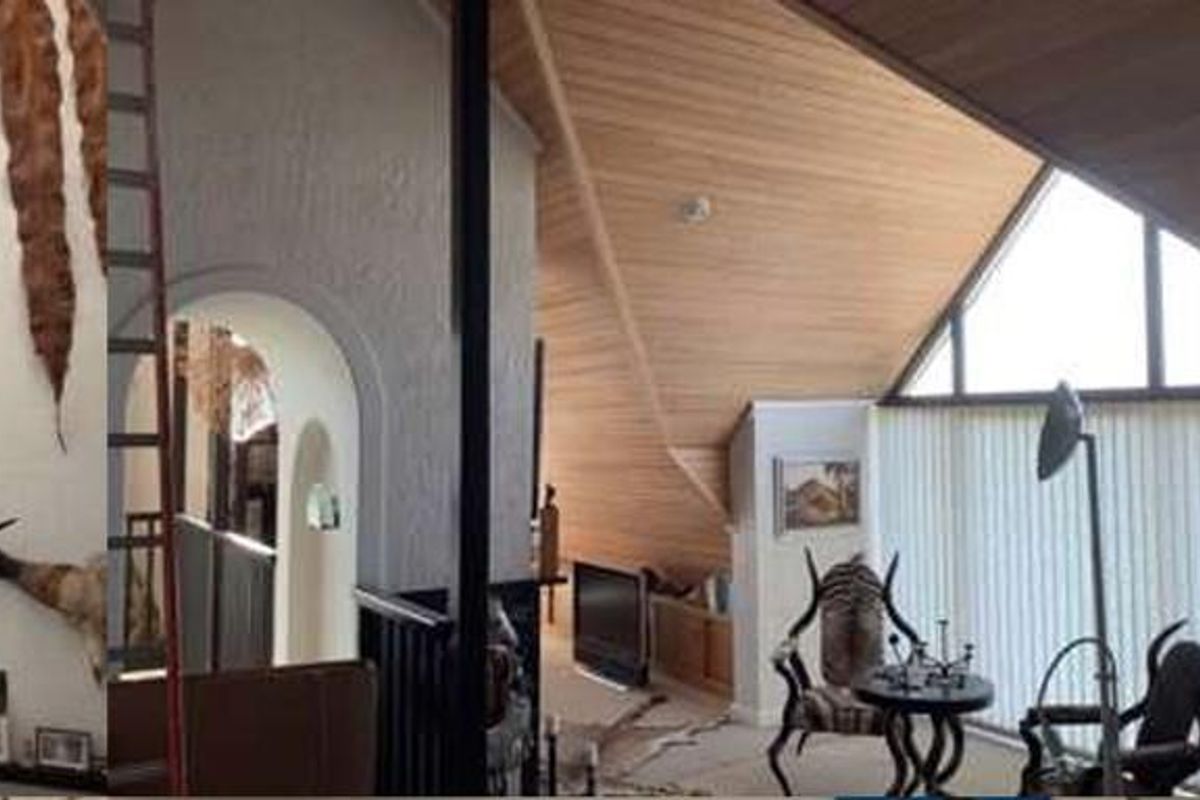 A unique living area featuring high vaulted timber-clad ceilings, large triangular windows, and architectural arched transitions between spaces.