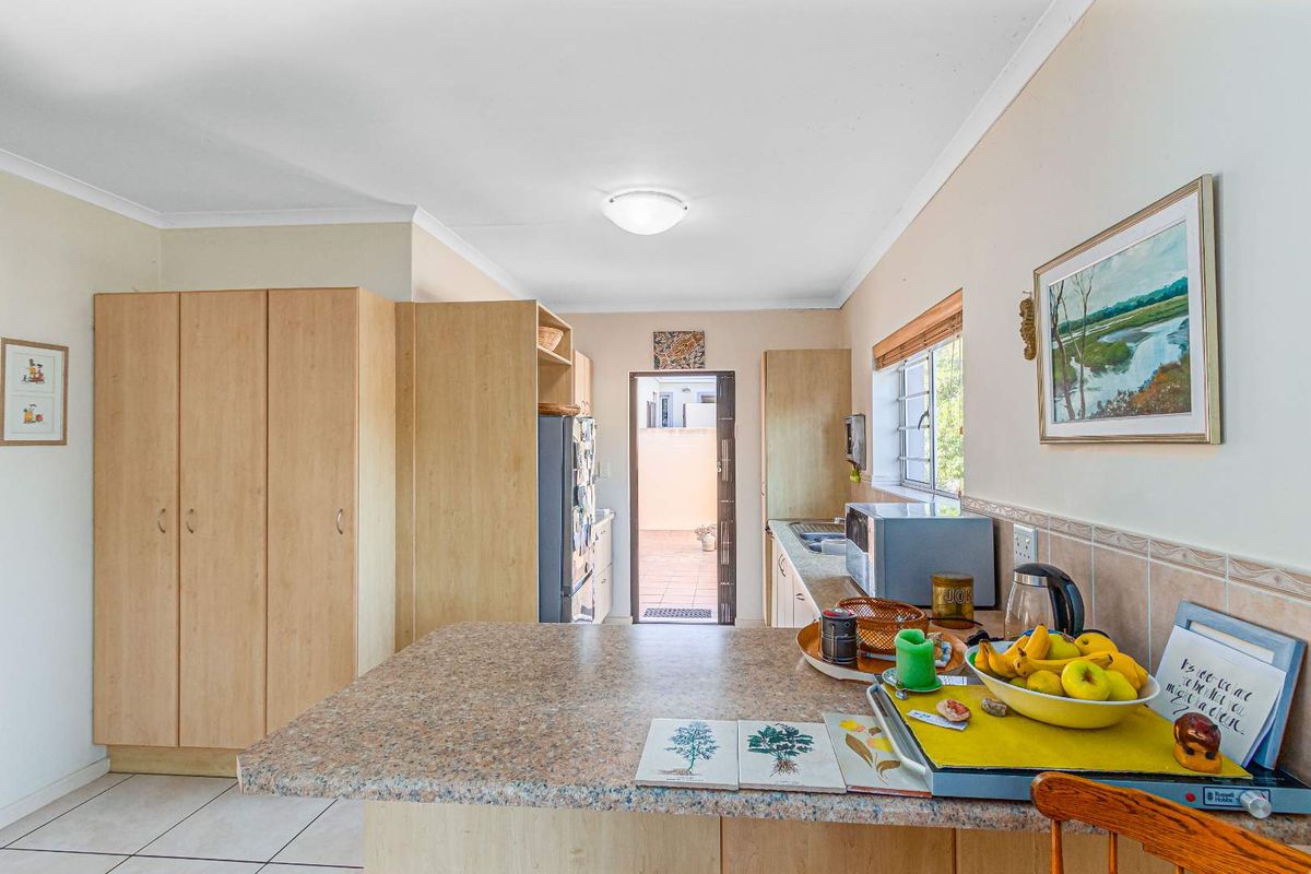 Functional kitchen featuring light wood-look cabinetry, laminate countertops, tiled flooring, and direct access to an exterior courtyard area.