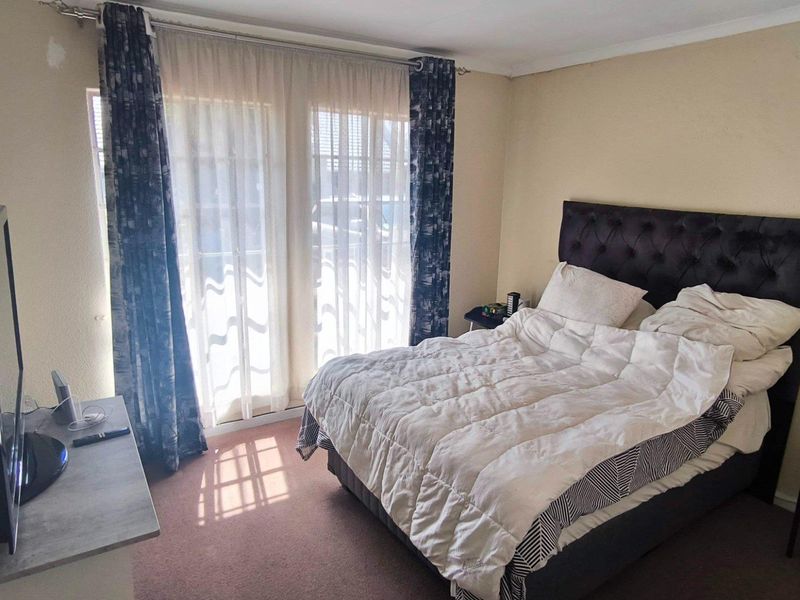 A bedroom featuring carpeted flooring and a sliding glass door providing natural light, with some minor wall surface wear visible.