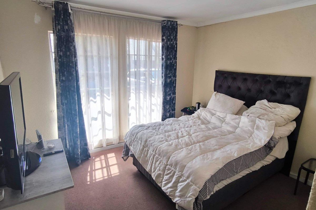 A bedroom featuring carpeted flooring and a sliding glass door providing natural light, with some minor wall surface wear visible.