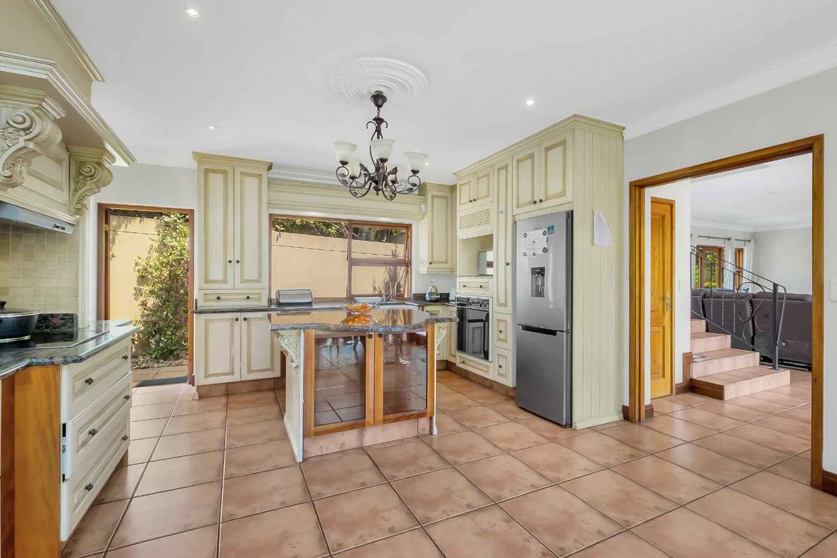 Spacious kitchen featuring classic cabinetry, granite countertops, a central island, and tiled flooring, with direct access to an outdoor area.
