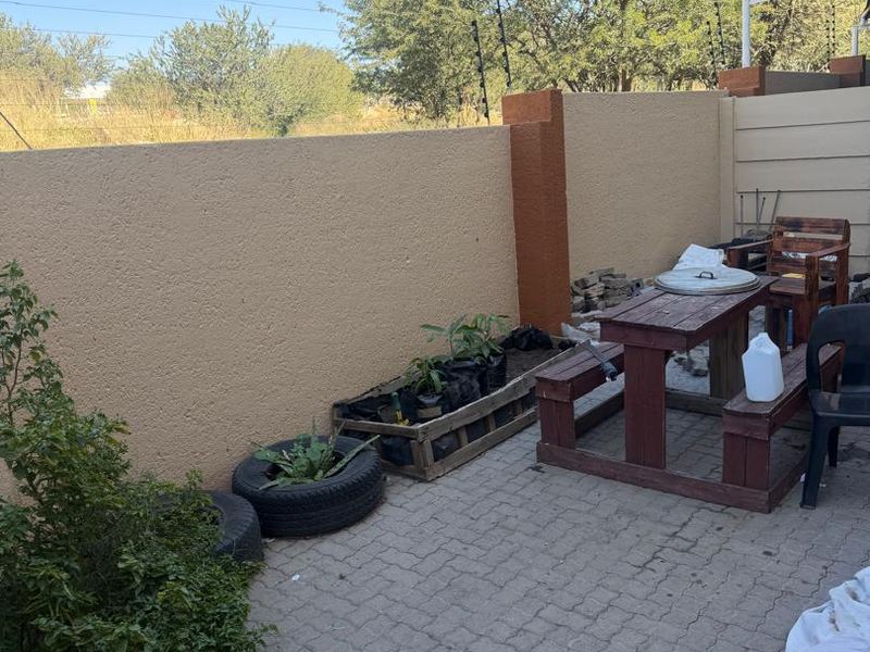 A private rear courtyard featuring paved flooring and high boundary walls with electric fencing, offering a functional outdoor space.