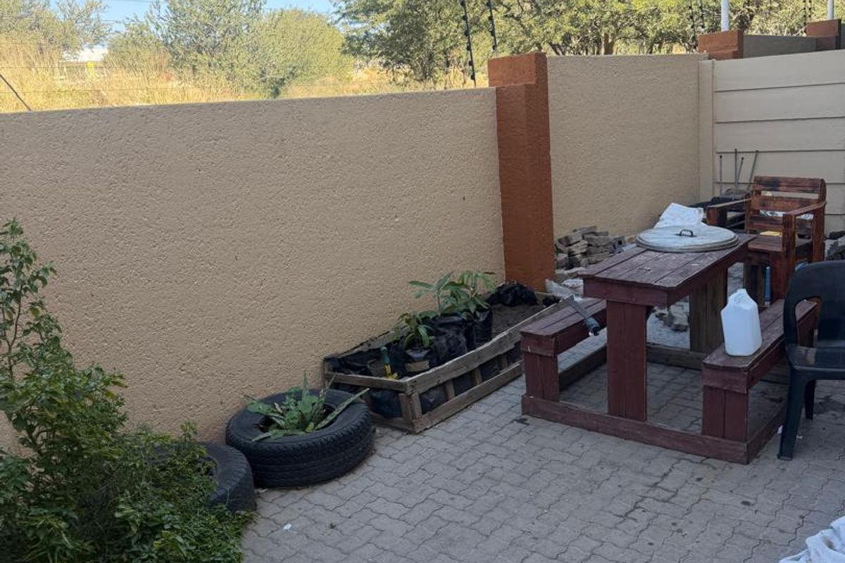 A private rear courtyard featuring paved flooring and high boundary walls with electric fencing, offering a functional outdoor space.