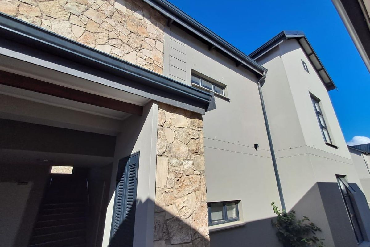 A view of the rear building facade featuring stone cladding, plastered walls, and modern window fixtures.